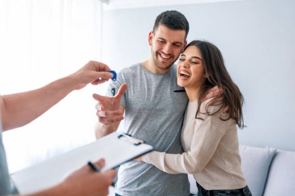 Pareja feliz de jóvenes que acaban de recibir su propiedad después del proceso de venta de casas